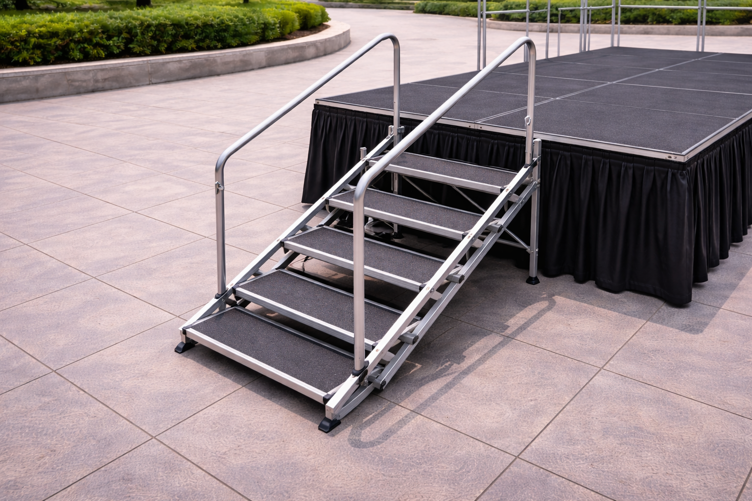 Escalera modular de aluminio con barandillas instalada junto a un escenario portátil para actos culturales municipales en exterior