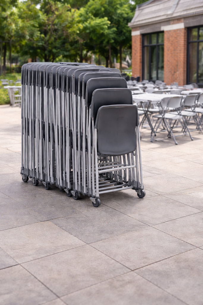 Sillas plegables apiladas en carros para eventos culturales y actos municipales.